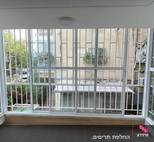 חלונות עם תריסים לבנים במרפסת סגורה